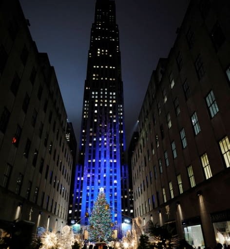 Smukły gmach nowojorskiego wysokościowca Rockefeller Center góruje ponad świetlistą choinką. Potężny gmach Rockefeller Center w nowym Jorku góruje ponad świetlistą choinką