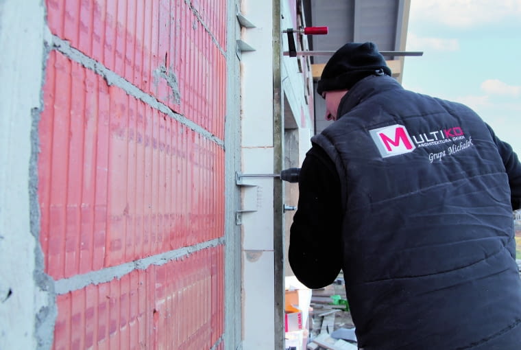 Belki z twardego polistyrenu z zatopionymi w nich wspornikami stalowymi służą do poszerzenia ościeża i wykonania ramy nośnej skutecznie przenoszącej siły pochodzące od konstrukcji okiennych Belki z twardego polistyrenu z zatopionymi w nich wspornikami stalowymi służą do poszerzenia ościeża i wykonania ramy nośnej skutecznie przenoszącej siły pochodzące od konstrukcji okiennych