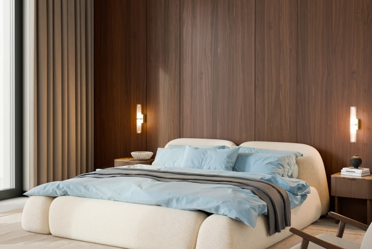 Ściana wykończona ciemnym drewnem pochłania światło, dzięki czemu sypialnia zyskuje bardziej nastrojową, otulającą aurę. Ustawione przy takiej powierzchni łóżko Wolke w beżowej tapicerce bouclé prezentuje się stabilnie i w pełni „zaprojektowane”.