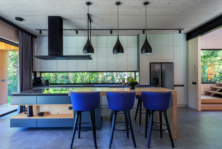 Ważną rolę w otwartej kuchni odgrywa wyspa – jedna jej część jest wykonana z granitu, a druga z drewna, tego samego, z którego powstała konstrukcja domu w technologii CLT Ważną rolę w otwartej kuchni odgrywa wyspa – jedna jej część jest wykonana z granitu, a druga z drewna, tego samego, z którego powstała konstrukcja domu w technologii CLT