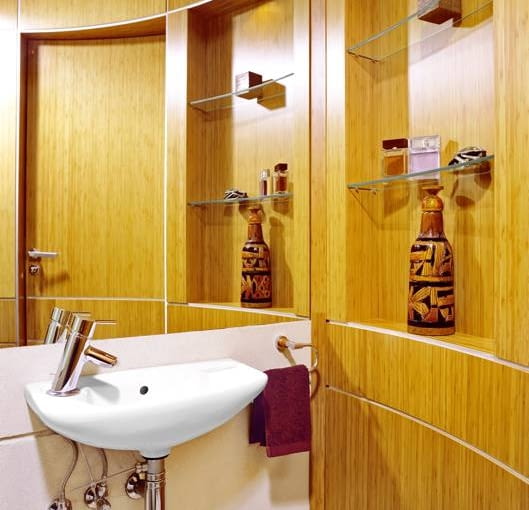 Naturalnie. Najbardziej rzucającym się w oczy elementem dekoracyjnym jest łukowata ściana wykończona bambusowym fornirem. Na szklanych półeczkach wyeksponowano ozdobne drobiazgi.