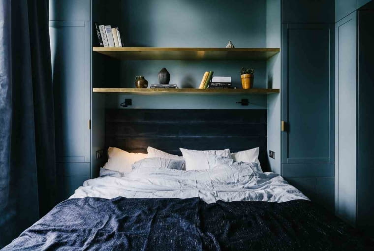 Z kolei sypialnia tonuje nastroje, by móc się wyciszyć po dniu pracy i nastroić na dobry sen. Zaaranżowano ją w nieco buduarowym stylu: ściany wraz z zabudową pokryte są farbą w kolorze szaro-niebieskim, ocieplone mosiężnymi półkami. Jest miękko i nastrojowo.