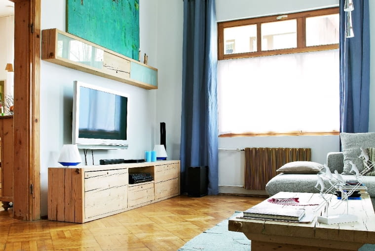 JASNE DREWNO I BŁĘKIT rozświetlają wnętrze. Nawet obraz Małgorzaty Rosińskiej, zakopiańskiej malarki, dobrano pod kolor; choć powinien wisieć na wysokości oczu, wsparto go na półce nad telewizorem.