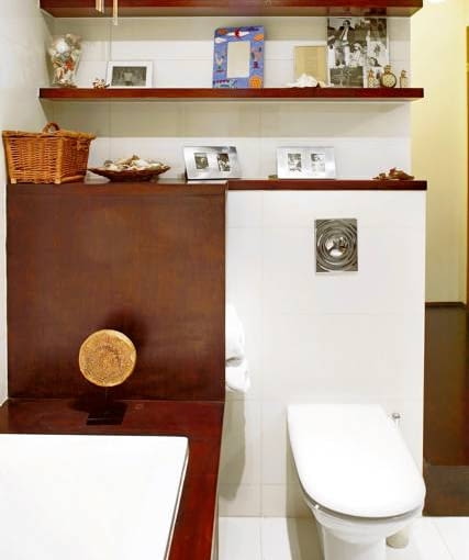 Między wanną a ścianką instalacyjną znajduje się osłonięta ekranem półka, na której są przechowywane zrolowane ręczniki. Tajemnicza ozdoba na ekranie to magiczny krąg życia - jedna z pamiątek przywiezionych przez właścicielkę z podróży po świecie.