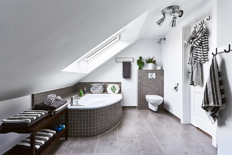 Do łazienki na poddaszu konsekwentnie wybrano płytki z Opoczna. Ceramika jest z firmy Cersanit. Spokojną szarość ożywia soczysta zieleń (metalowy kaktus i kosze na wannie są ze sklepu właścicielki).