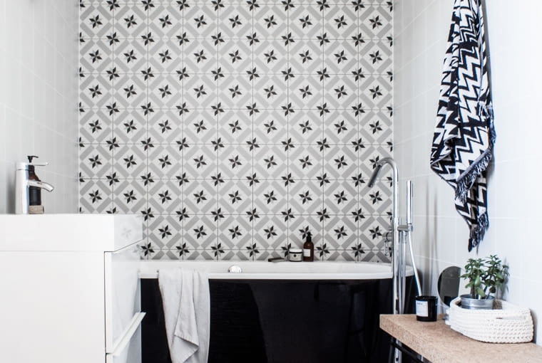 Druga łazienka ma charakter pokoju kąpielowego z wolnostojącą czarną wanną umieszczoną na tle kafli o intensywnym wzorze.