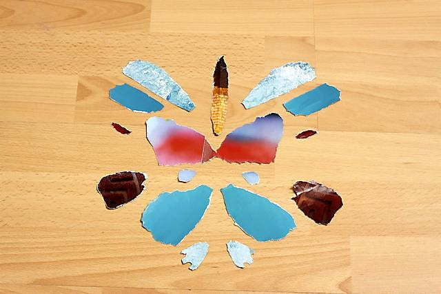 2. Kawałki kolorowego papieru, np. kartki z czasopism, składamy na pół i wydzieramy z nich symetryczne elementy motyla.