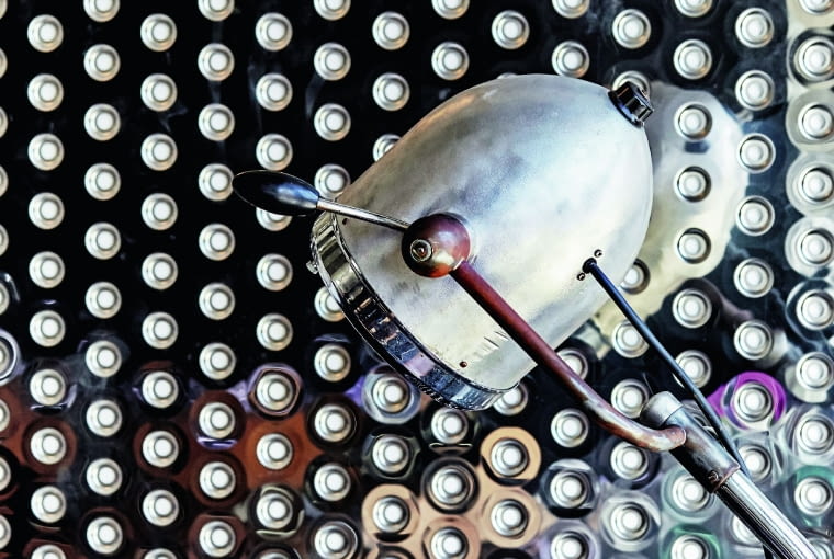 Dentystyczna lampa z kolekcji smallna na tle drzwi z polerowanej blachy perforowanej 3+ by Zięta. Dentystyczna lampa z kolekcji smallna na tle drzwi z polerowanej blachy perforowanej 3+ by Zięta.