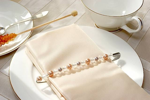 Z agrafki i koralików. Na dużą agrafkę używaną do łapania oczek w robótkach na drutach nakładamy koraliki. Serwetkę składamy tak, by zmieściła się w agrafce. WNETRZA DEKORACJE OBRACZKA NA SERWETKE