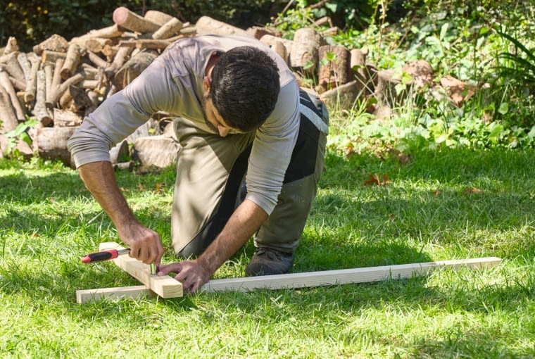 Krok 4. Złóż elementy Połącz ze sobą ruchome elementy i wykonaj połączenia śrubowe – najdłuższy kawałek drewna służy jako podstawa, na której należy przykręcić najpierw średni, a następnie mały kawałek drewna. Można tutaj wykorzystać śruby z łebkiem półokrągłym. Pod każdą z nich dodaj podkładkę, a na wierzchu zamocuj nakrętkę samozabezpieczającą. Dokręć każde połączenie śrubowe za pomocą grzechotki mocno, ale by można było poruszać drewnianymi elementami i złożyć koziołek drewniany.