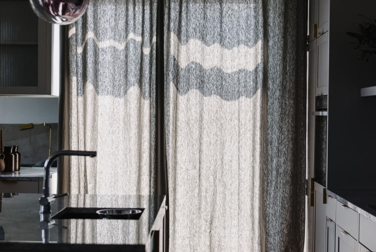 Transparentna lampa Capsule firmy Brokis oświetla wyspę kuchenną, gdy zapada zmrok.