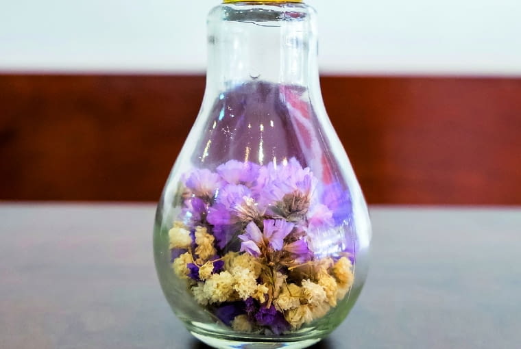 Kwiatowy flakon z żarówki wyjmujemy środek (instrukcji szukajmy w internecie), ustawiamy ją na stabilnej podstawce (np. uszczelce) i napełniamy suszonymi kwiatkami.