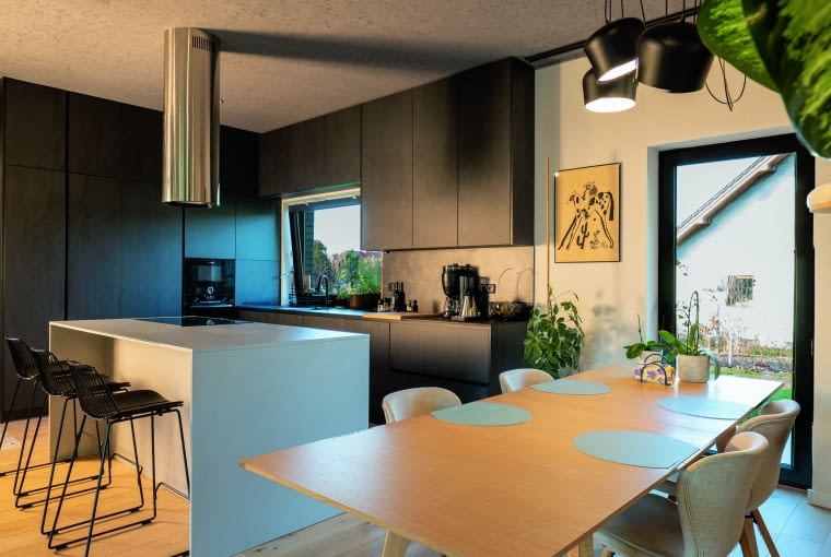 Salon połączony z kuchnią jest ulubionym miejscem mieszkańców. Króluje tu drewno: dąb na podłodze – wysokiej klasy i ręcznie obrabiany, dąb w stole jadalnianym, a do tego wyspa kuchenna i fronty szafek ze zwykłych blatów drewnianych Salon połączony z kuchnią jest ulubionym miejscem mieszkańców. Króluje tu drewno: dąb na podłodze – wysokiej klasy i ręcznie obrabiany, dąb w stole jadalnianym, a do tego wyspa kuchenna i fronty szafek ze zwykłych blatów drewnianych