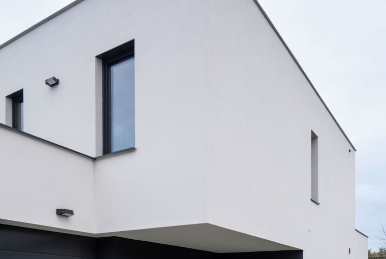 ...a tu wjazd do trzystanowiskowego garażu i miejsca postojowe dla gości. Oba zewnętrzne trakty komunikacyjne wydzielono tak, by ich użytkownicy nie tylko nie wchodzili sobie w drogę, ale nawet pozostawali dla siebie częściowo niewidoczni Dom z kostki