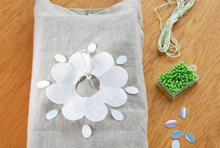 <B>Krok 4.</B> na wierzchu przyszywamy brzegi kwiatka mocnym ściegiem na okrętkę. Doszywamy cekiny i koraliki. Ostrymi nożyczkami wycinamy środek kwiatka - przez ten otwór będziemy wyciągać chusteczki. PUDELKO NA CHUSTECZKI JEDNORAZOWE W DEKORACYJNEJ TOREBCE - WYKONANIE STYLIZACJA JOLANTA I KINGA KOLARY FOT. RADOSLAW WOJNAR PUBLIKACJA CZTERY KATY NR 6 (176) - 6.2006 SLOWA KLUCZOWE: BUTIK PLASTYKA