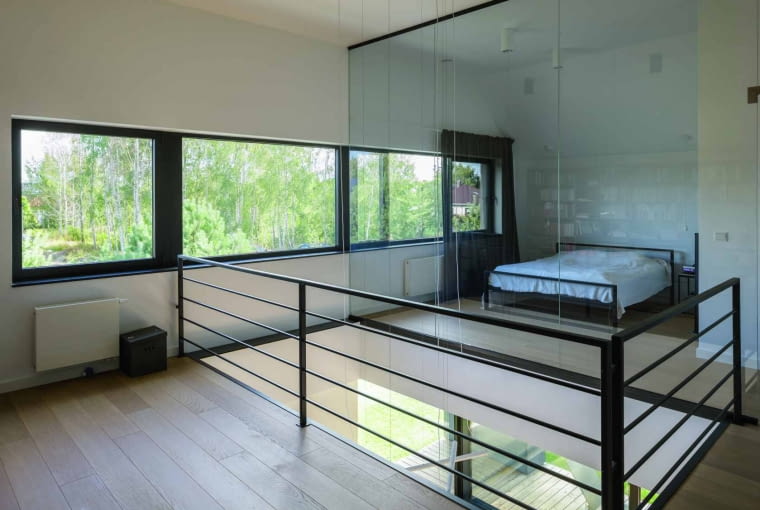 Wokół pustki nad salonem stworzono część otwartą piętra. Składa się na nią przestrzeń przeznaczona do pracy „gabinetowej” (z lewej) i transparentna sypialnia za szybą Wokół pustki nad salonem stworzono część otwartą piętra. Składa się na nią przestrzeń przeznaczona do pracy „gabinetowej” (z lewej) i transparentna sypialnia za szybą