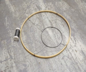 Krok 1: Połącz drewnianą obręcz i obręcz z drutu falistego za pomocą drutu rzemieślniczego. Użyj drutu o różnych długościach, aby stworzyć asymetryczną podstawę.