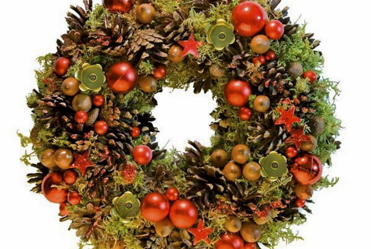 Ozdoby adwentowe. Wieniec z szyszek, czerwonych i rudych bombek oraz gałązek jałowca z małymi zielonymi świeczkami