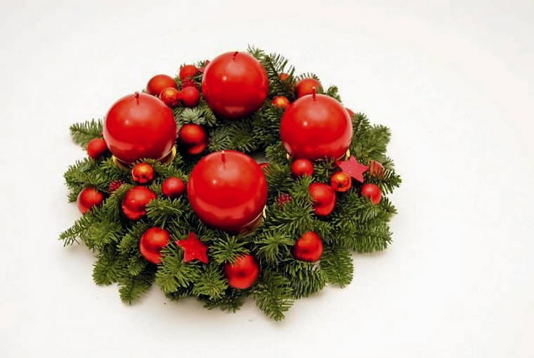 Ozdoby adwentowe. Wieniec z kulistymi świecami, małymi bombkami i czerwonymi gwiazdkami