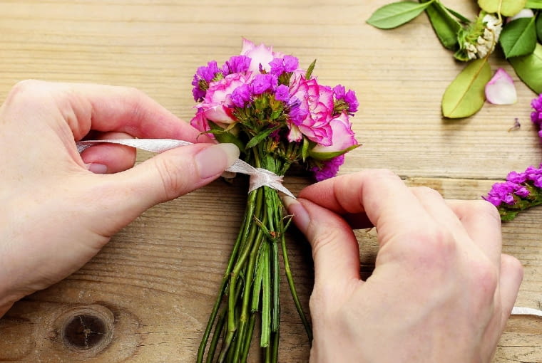 Ukwiecona bransoletka. Łodyżki róż (pozbawione kolców) związujemy wstążką tuż pod główkami kwiatów, tak by powstał zgrabny bukiecik, a końce wstążki swobodnie zwisały.