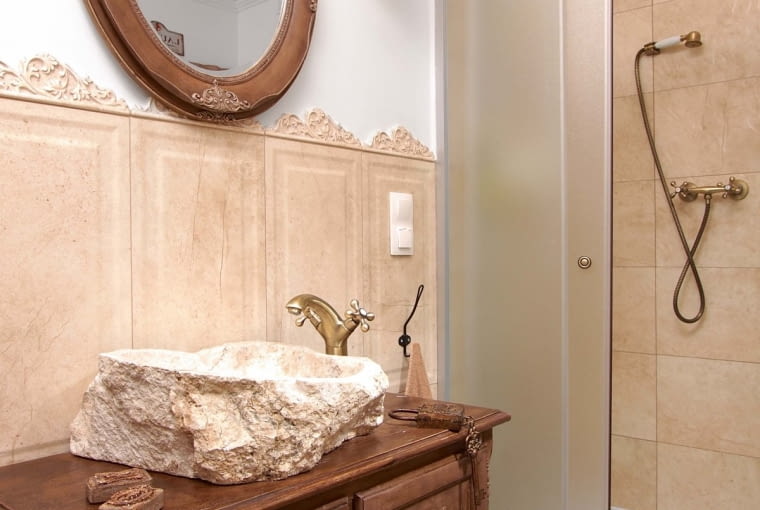 Ściany w łazience na parterze wykończono 'boazerią' z dużych terakotowych płytek zwieńczonych dekorami (wszystkie kafle są z firmy Tubądzin). Z taką dekoracją pięknie harmonizuje nablatowa umywalka wykonana z naturalnego kamienia (industone.pl).