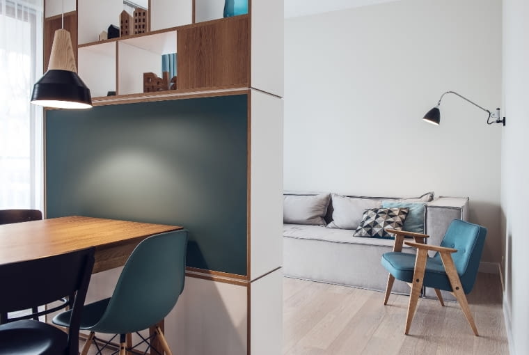 Gospodarze na co dzień mieszkają poza Trójmiastem, dlatego minimalistyczny kącik sypialniany na tę chwilę w zupełności im wystarcza. Oprócz dużej kanapy, regału na książki i ściennej lampy do czytania marki Gubi, znalazł się tu również wygodny fotel 366 Chierowskiego w kolorze ocean velvet.