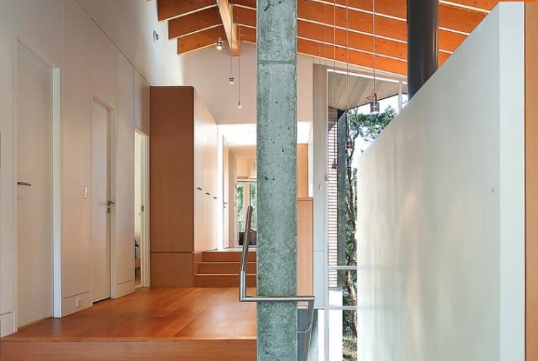 Schody wewnętrzne wznoszą się obok solidnej, betonowej ściany, która wspiera krokwie dachowe. To konstrukcyjne serce budynku. Tuż przy niej architekci zaplanowali korytarz prowadzący do bardziej intymnych pomieszczeń: sypialni dzieci oraz właścicieli. W głębi znajduje się łazienka. dom na urwisku, nowoczesny dom