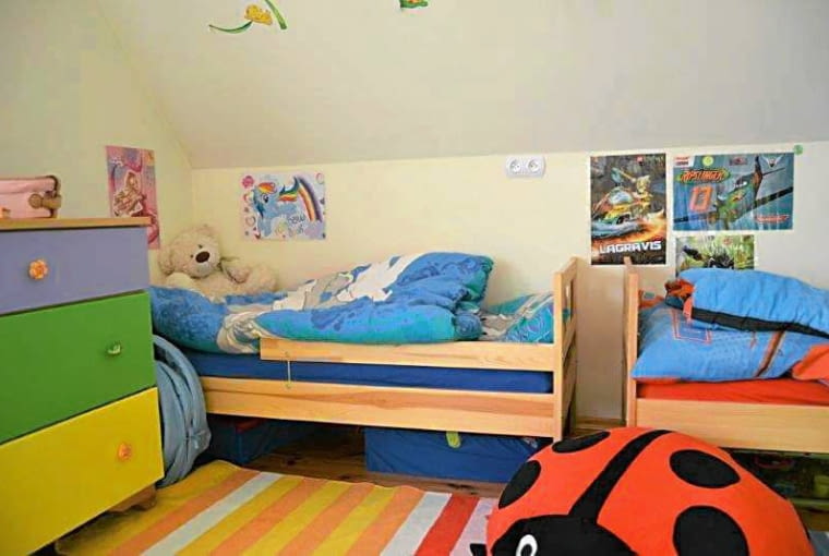 PRZED ZMIANĄ. Dwa drewniane łóżka stały przy ścianie pod skosem dachu. Resztę pokoju zajmowały regały i kontenerki na zabawki. pokój dziecięcy, aranżacje wnętrz