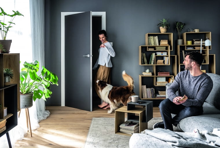 Prosty model drzwi o gładkiej powierzchni w kolorze ściany kontrastuje z drewnianą posadzką w jasnym kolorze Prosty model drzwi o gładkiej powierzchni w kolorze ściany kontrastuje z drewnianą posadzką w jasnym kolorze