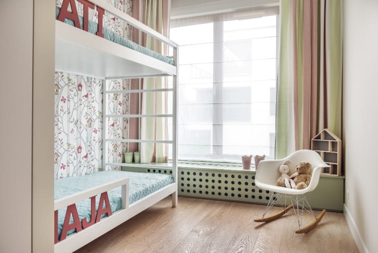 Pokój dziewczynek odbiega kolorystycznie od pozostałej części mieszkania. Rola architektki polegała na delikatnym przygaszeniu koloru różowego i zestawieniu go z pastelową zielenią. To celowy zamysł - stłumione kolory wyglądają, jakby były narysowane kredkami i działają na wyobraźnię dzieci. W tym pomieszczeniu również maksymalnie wykorzystano małą przestrzeń. Łóżko jest piętrowe, a zabudowa pod oknem służy jako miejsce do przechowywania zabawek.