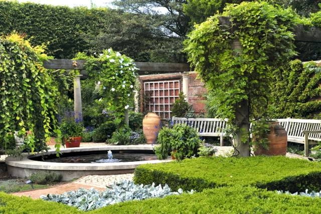 Nastrój tego ogrodu zbudowano na zasadzie kontrastu - tworzą go uporządkowane niskie partery z bukszpanu i swobodne 'słupy' pnączy, które zastępują drzewa