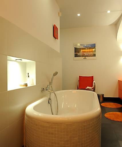 Nad owalną wanną zrobiono niewielką oświetloną wnękę. Chociaż pełni ona przede wszystkim praktyczną funkcję (stoją tam kosmetyki potrzebne do kąpieli), ma niebagatelny wpływ na dekoracyjność pomieszczenia.