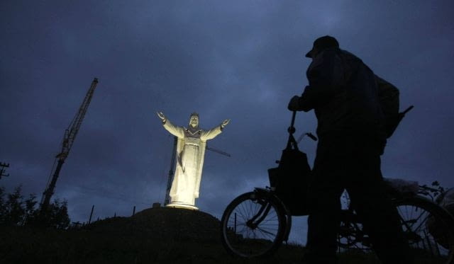 Statua Chrystusa ukończona A man pushes his bicycle past a giant statue of Jesus Christ in Swiebodzin, 110 km (68 miles) west of Poznan, western Poland, November 6, 2010. The statue of Jesus Christ that its builders say will be the largest in the world is fast rising from a Polish cabbage field and local officials hope it will become a beacon for tourists. To match Reuters Life! POLAND-JESUS/ REUTERS/Kacper Pempel (POLAND - Tags: RELIGION SOCIETY)