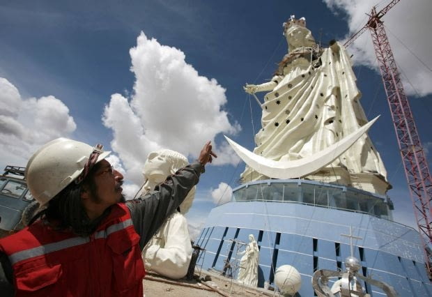 Bolivian sculptor Rolando Rocha points at the Virgin of the Socavon (patron saint of miners) statue during its construction at the Santa Barbara hill in the outskirts of the Oruro, some 200 km (124 miles) south of La Paz, January 18, 2013. The statue measures 45 metres (148 feet) in height and stands at 3850 meters (12,631 feet) above sea level. The statue is expected to complete by February 2, 2013 according to its sculptors. REUTERS/David Mercado (BOLIVIA - Tags: RELIGION SOCIETY)