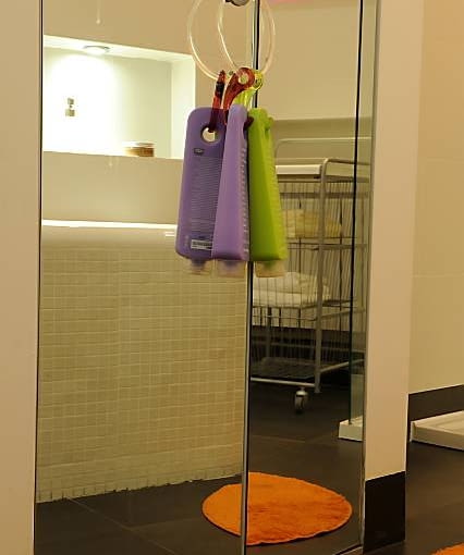 We wnęce za wanną stoi ażurowy regalik na ręczniki - pozostałe praktyczne rzeczy są schowane w szafie. Kosmetyki w barwnych opakowaniach wiszące na gałce drzwi lustrzanej szafy stanowią efektowny akcent kolorystyczny w tym wnętrzu.