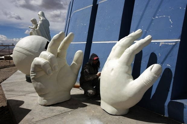A sculptor works on the hands of a statue of Jesus as a child which is part of the Virgin of the Socavon (patron saint of miners) statue during their construction at the Santa Barbara hill in the outskirts of the Oruro, some 200 km (124 miles) south of La Paz, January 18, 2013. The Virgin of the Socavon statue measures 45 metres (148 feet) in height and stands at 3850 meters (12,631 feet) above sea level. The statue is expected to complete by February 2, 2013 according to its sculptors. REUTERS/David Mercado (BOLIVIA - Tags: RELIGION SOCIETY)