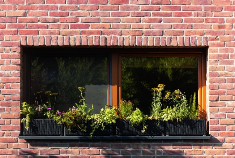 To okno bocznej elewacji, umieszczone koło ogrodowego tarasu, doświetla jadalnię. Do stworzenia tarasu wykorzystano jedną z dwóch wnęk wykrojonych w bryle, ale prawdę mówiąc wycięcia urozmaicające budynek pojawiają się również wokół okien, choć na znacznie mniejszą skalę