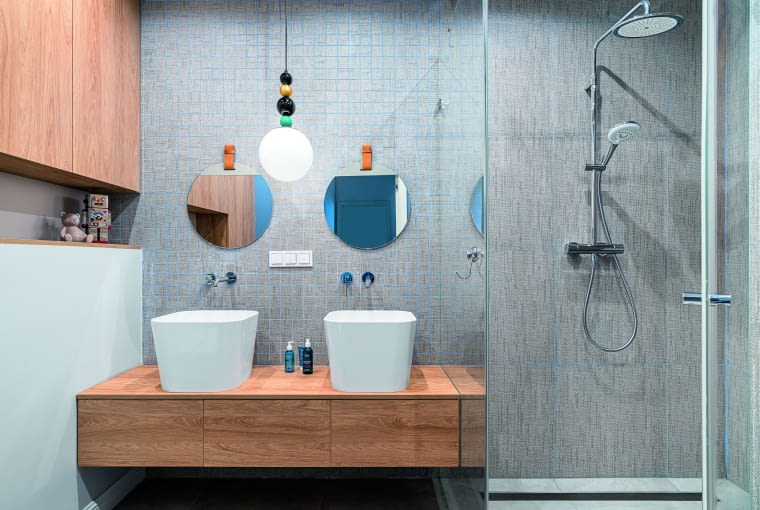 W łazience synów każdy ma swoją umywalkę i lustro, oczywiście okrągłe. Niebieski kolor, charakterystyczny dla pokoi dzieci, został tu przemycony pod postacią fug łączących płytki ścienne. W łazience synów każdy ma swoją umywalkę i lustro, oczywiście okrągłe. Niebieski kolor, charakterystyczny dla pokoi dzieci, został tu przemycony pod postacią fug łączących płytki ścienne.