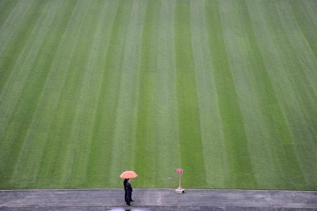A member of the media waits for the last piece of turf to be laid on the Olympic Stadium's field of play in London March 29, 2011. London hosts the Olympic Games from July 27 to Aug 12, 2012. REUTERS/Paul Hackett (BRITAIN - Tags: SPORT OLYMPICS)