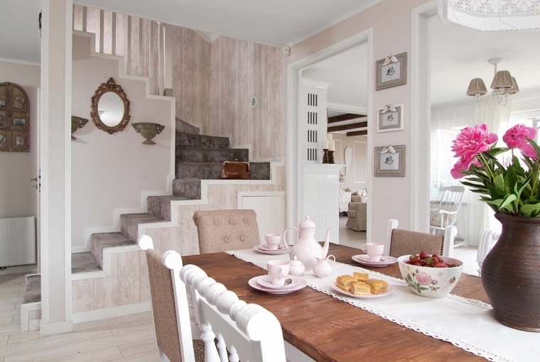 Schody pokryte wykładziną prowadzą na piętro, gdzie znajdują się sypialnie i jedna z łazienek. Dekoracyjne lustro pani domu kupiła w sklepie Netto i przemalowała na brązowo. Ściany przy schodach są wykończone tapetą imitującą deski (Leroy Merlin).