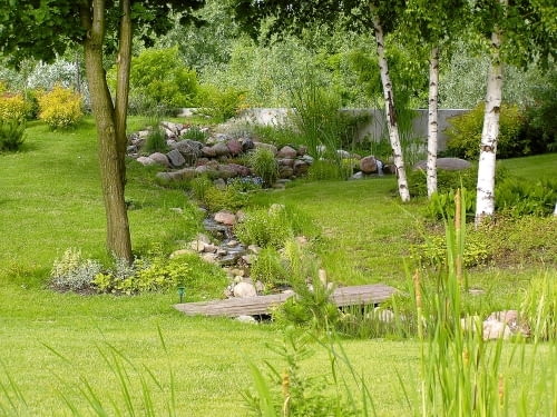 Strumień w górnym biegu - półtora metra powyżej poziomu gruntu na działce. Widoczny fragment betonowego muru to szczyt ściany oporowej wzdłuż sztucznego nasypu, który izoluje posesję od drogi.