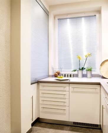 Wykorzystano nawet płytką wnękę przy oknie - zbudowano w niej półki na środki czystości. Na górze zasłania je roleta, na dole drzwiczki.