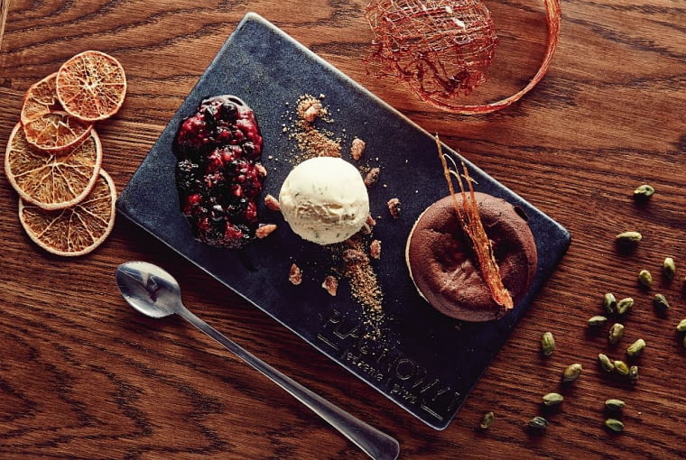 Fondant czekoladowy: kruche ciastko z gorącą płynną czekoladą, podane z cukrem z piernika, orzeszkami oraz konfiturą z owoców leśnych. Restauracja Plac Nowy 1, wnętrza, trendy