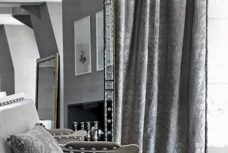 Zasłonę oraz poduszkę wykonano z tkaniny Eos. Bogaty barokowy wzór jest tylko o ton jaśniejszy od tła, dlatego wydaje się bardzo subtelny. Tak zaprojektowany materiał, mimo historycznego pochodzenia,świetnie sprawdzi się we wnętrzach współczesnych. Dostępny w pięciu wersjach kolorystycznych, Houles.