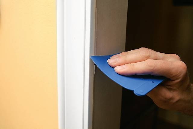 Profile i dekoracyjne narożne kostki mocujemy do ściany klejem do poliuretanu. Preparat nakładamy ciągłą linią na brzegi elementów. Po dociśnięciu ich do futryny ściągamy nadmiar kleju szpachelką. Jeśli klej nie wypełnił szpar, uzupełniamy je szpachlą.