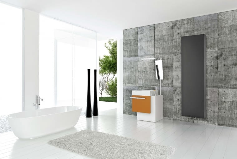 KROPLA KOLORU. Ściana wyłożona płytami z betonu, geometryczne sprzęty w tym czarny prostokąt grzejnika, który idealnie wpisuje się w nowoczesną, harmonijną ale sprawiającą wrażenie chłodnej, aranżację. Jak ją ocieplić, nie psując minimalistycznego stylu? Najłatwiej, dodając kolorową płaszczyznę, choćby niewielką, jak np. front umywalkowej szafki. purmo.com/pl