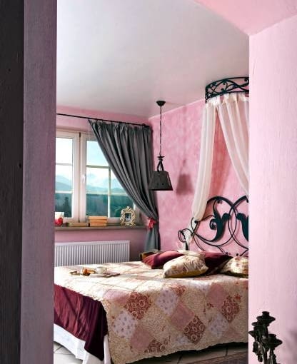 SYPIALNIA PO ZMIANIE. Kolorystykę narzuciła nazwa apartamentu - Różowy. Aby nadać ścianom wygląd starego muru, nierównomiernie położono na nie chropawy (zmieszany z piaskiem) tynk i pomalowano techniką przecierek na kilka odcieni różu. Metamorfoza. Pokój. Sypialnia.