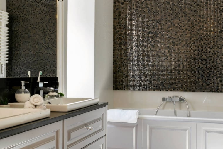 ŁAZIENKA. Obudowę wanny zrobiono z tego samego materiału co łazienkowe szafki - z płyty MDF do złudzenia przypominającej drewniane fronty z płycinami. Dzięki temu podkreślono stylistyczną spójność wnętrza.