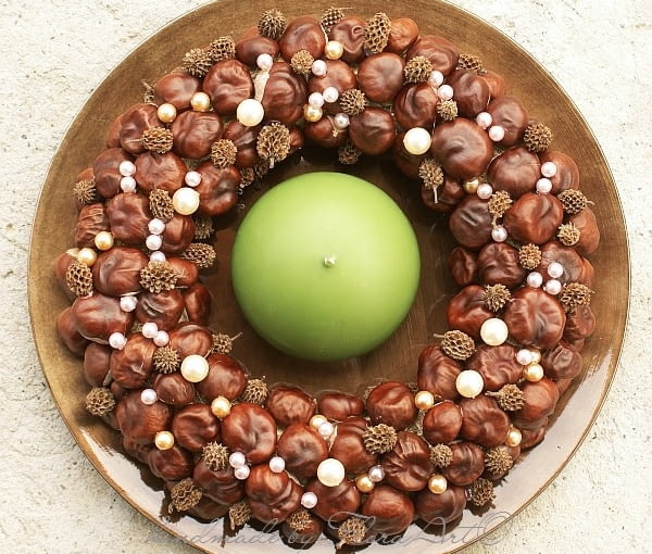 Wianki i stroiki bożonarodzeniowe. Wianek z kasztanów, perełek i drobnych egzotycznych owocków. Z matową świecą na błyszczącym talerzu. Jako jesienno-zimowa dekoracja stołu. Przed nami adwent i Boże Narodzenie