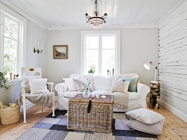 W jasnym salonie króluje duża, miękka sofa. mały domek, drewniany domek, dom w Szwecji, wnętrza, skandynawski styl